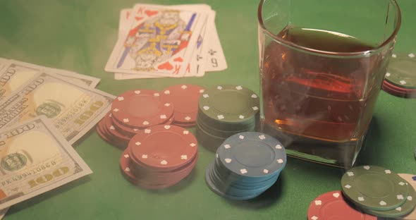 Chips Cards a Glass of Whiskey and Money are on the Green Gaming Table
