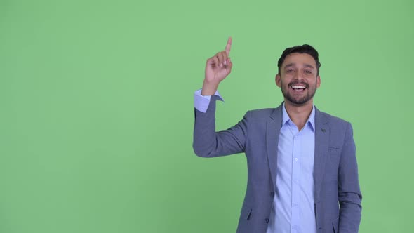 Happy Young Bearded Persian Businessman Talking While Pointing Up