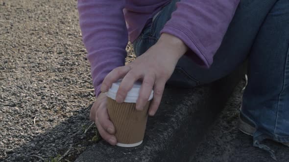 Sitting on the sidewalk drinking takeout coffee medium shot