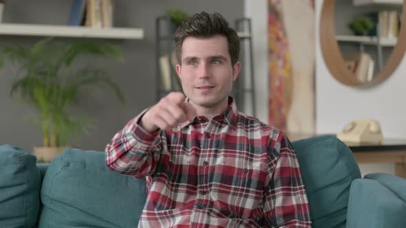 Portrait of Man Pointing at the Camera While Sitting on Sofa