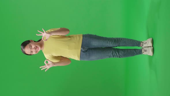 Full Body Of A Happy Young Asian Kid Girl Showing Okay Gesture To The Camera In The Green Screen