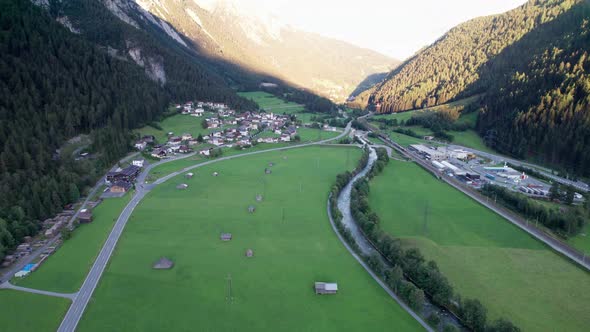 Road in Austrian Alp Valley Between Green Fields and Wooden Houses Aerial View