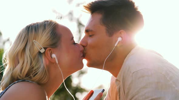 Happy Couple with Smartphone and Earphones Kissing