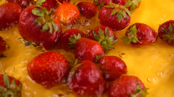 Falling strawberries into the water on an orange background. Slow motion.