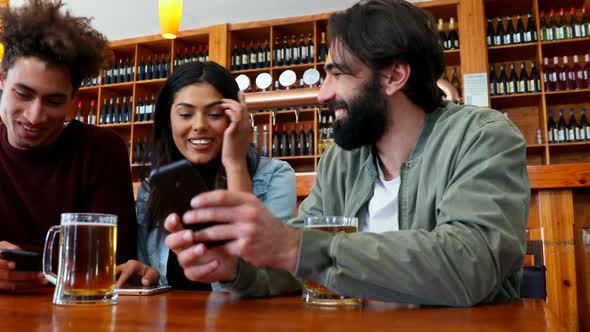 Friends using mobile phone while having beer 4k