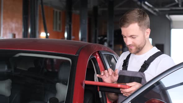 An American Mechanic Maintains the Vehicle with the Help of Computer Diagnostics Modern Equipment