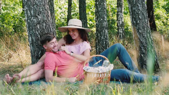 Picnic Time. Happy Young Couple Having Fun. Man Laying on Her Hands. Outdoors in the Park