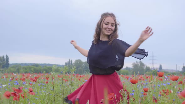 Cute Young Girl Running and Dancing in a Poppy Field Smiling Happily. Connection with Nature