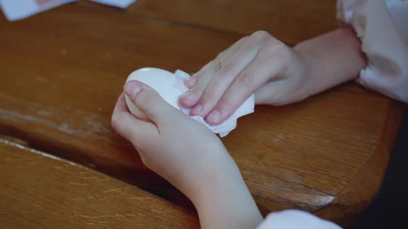 Young Girl's Hands Wipe Eggs for Painting at Wooden Table