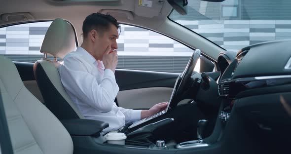 Shocked Businessman Scared By Reading Bad Email on His Laptop Computer Sitting in the Driver's Seat