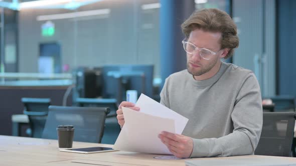 Young Businessman Reacting to Loss While Reading Documents