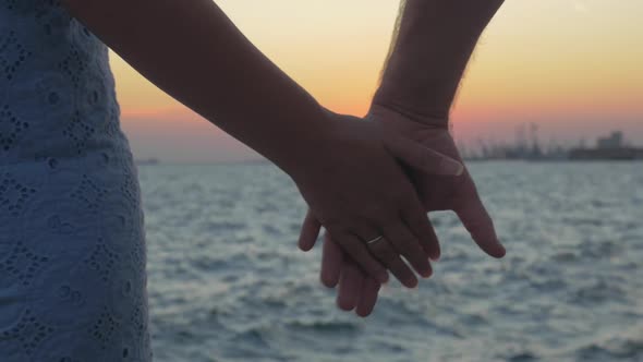 Close-up Shot of Romantic Couple Holding Hands on the Beach Against Sunset Piraeus, Greece