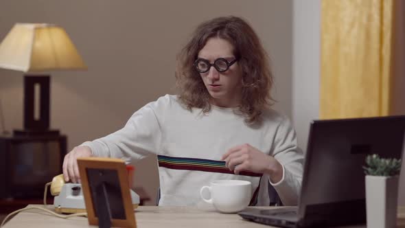 Confident Nerd Young Man Putting on Retro Eyeglasses and Picking Up Phone