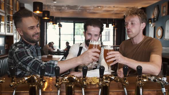 Three Man Friends Sitting in a Bar and Drinking Beer
