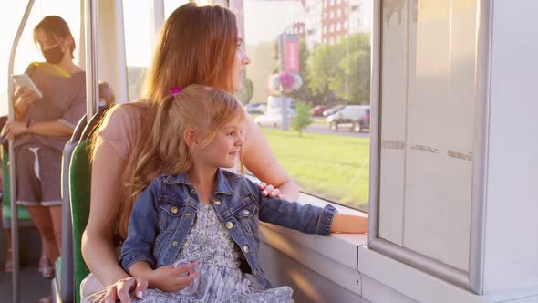 Family Rides in Public Transport Woman with Little Child Girl Sit Together and Look Out Window Tram