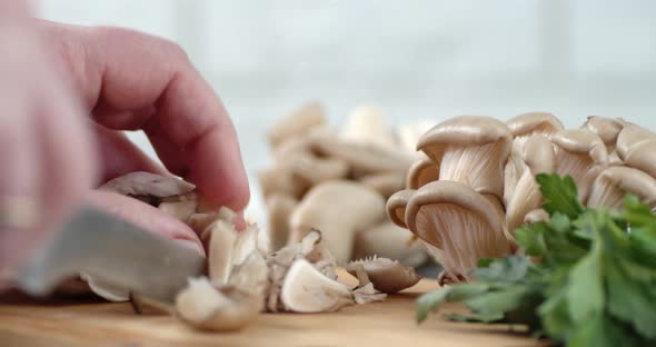 Male Hands Cut a Bunch of Fresh Mushrooms Into Pieces