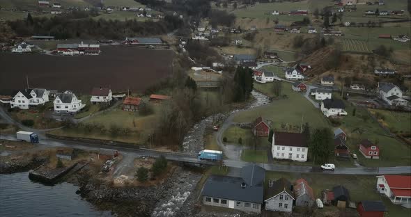Aerial shot of Cars passing small bridge over stream in Utvik village, Norway