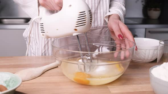 Beating Eggs And Mixing With Sugar Using Electric Mixer In A Glass Bowl. close up