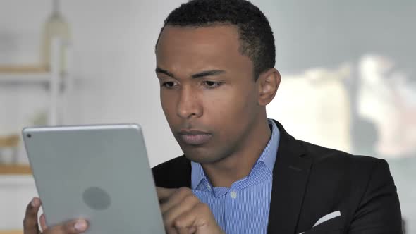 Close Up Of Casual AfroAmerican Businessman Surprised By Results While Using Tablet