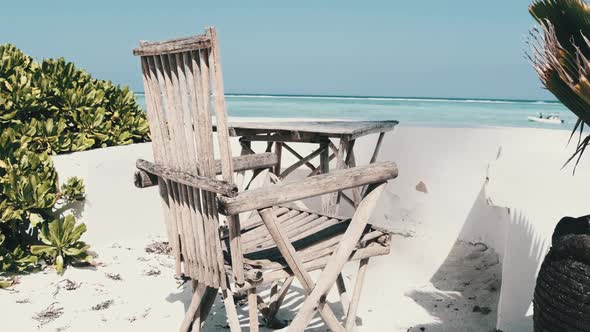 Dry SunFaded Table and Chair Overlooking Azure Beach and Indian Ocean Zanzibar