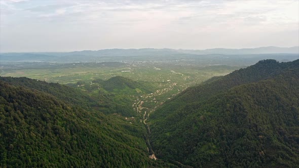 Aerial drone view of nature in Georgia. Valley with village, hills slopes covered with greenery, tow