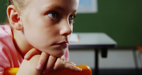 Upset girl sitting in classroom at school