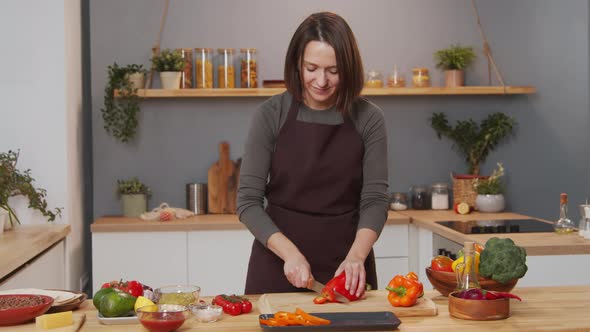 Woman Cutting Bell Pepper at Kitchen Table