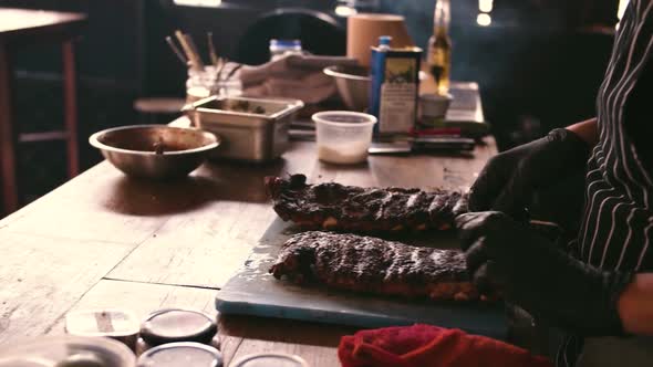Chef in black gloves is preparing spare ribs. Video footage from the kitchen.
