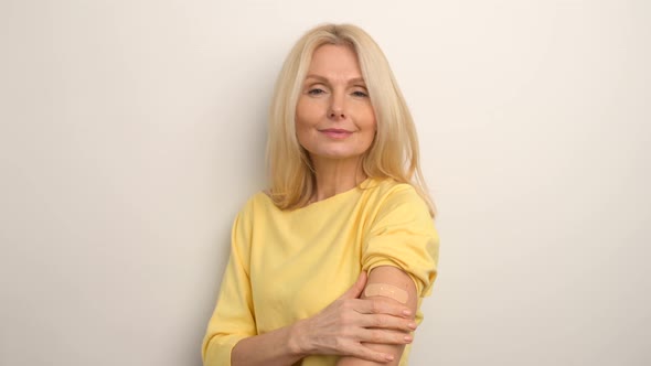 Happy Mature Lady on White Empty Blank Studio Background Looking at Her Hand