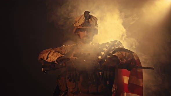 An American Soldier Stands with a Flag on His Right Shoulder