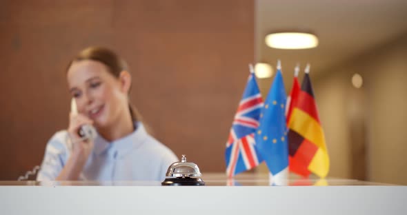 Young Female Receptionist Answering Phone at Hotel Front Desk