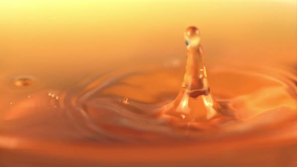 The Super Slow Motion Drop Falls Into the Apple Juice with Splashes