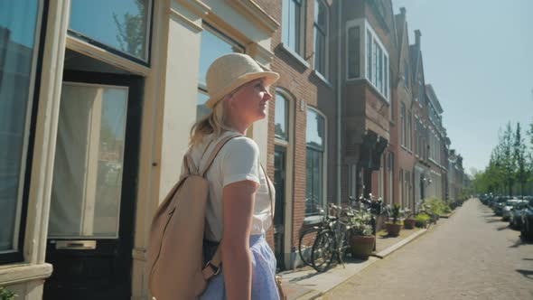 A Woman in a Hat Is Enjoying a Stroll Through the Streets of Delft in the Netherlands