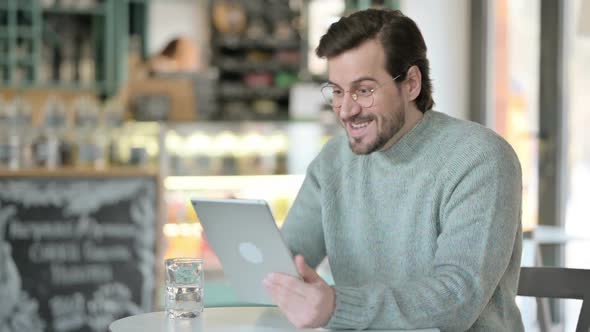 Successful Young Man Celebrating on Tablet in Cafe