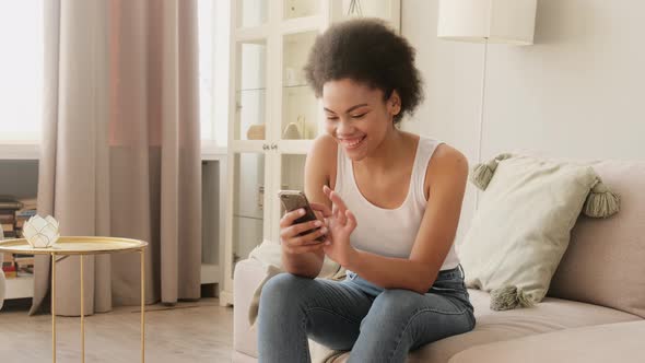 Amazed shocked african american woman, saying wow using phone