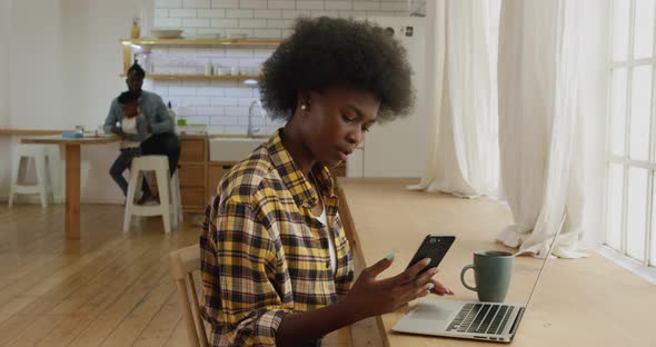 Woman using smartphone and laptop at home