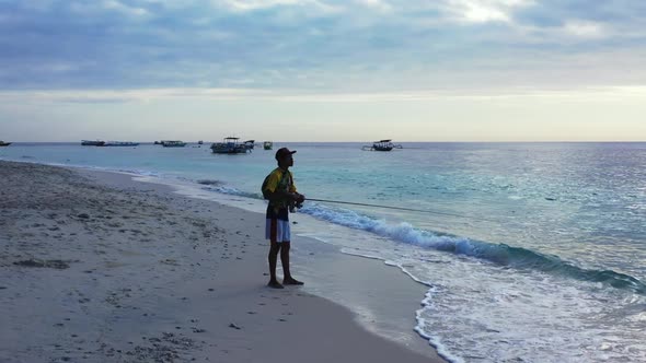 Single male fisherman on beautiful shore beach voyage by aqua blue sea and white sand background of 