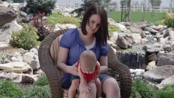 Slow motion of woman bouncing baby girl on her knee.