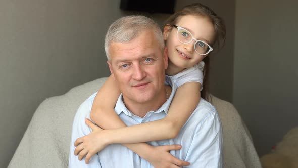 Family Portrait of Mature Father and Little Blonde Daughter Hugging at Home While Celebrating Father