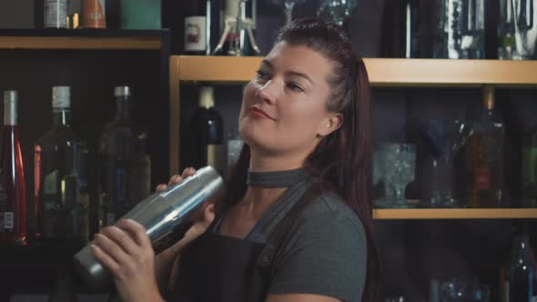 Dolly shot of female bartender shaking craft cocktail in bespoke speakeasy.