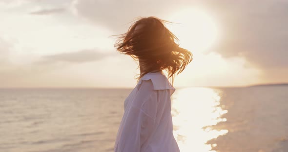 Silhouette of Young Woman Looks at the Sea Sunset From a Hill