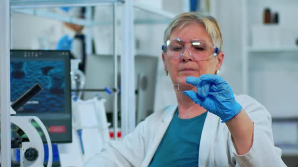 Senior Woman Lab Technician Looking at Virus Sample