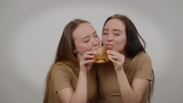 Twin Sisters Biting Chewing Delicious Tasty Sweet Bun Smiling Looking at Camera