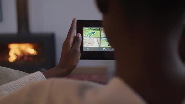 Back view of african american woman using smartphone and lying on sofa