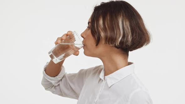 Young Beautiful Brunette East Asian Female in Shirt Drinking Water From Glass Then Smiling