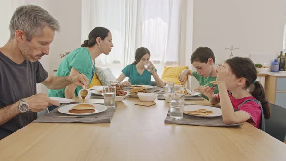 Family eating pancakes and fruits for breakfast