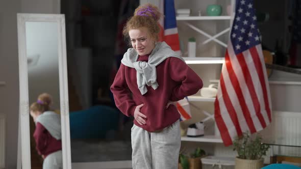 Young Caucasian Woman Suffering Stomach Ache Standing in Living Room at Home