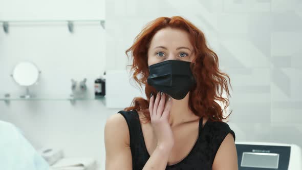 Woman in a Black Mask Sitting in the Doctor's Office and Looking at the Camera
