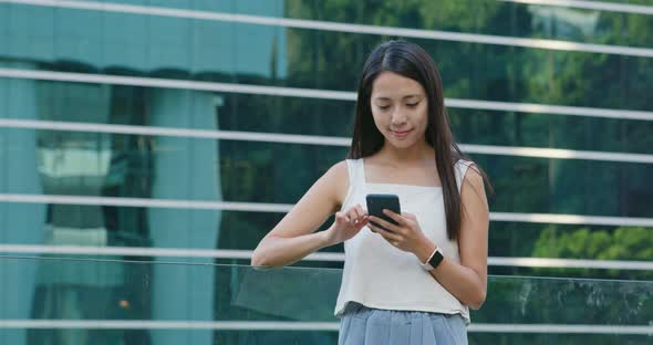 Woman use of smart phone with the office building background