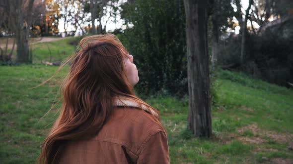 Desperate red haired woman alone in the park looking up.No escape,desperation